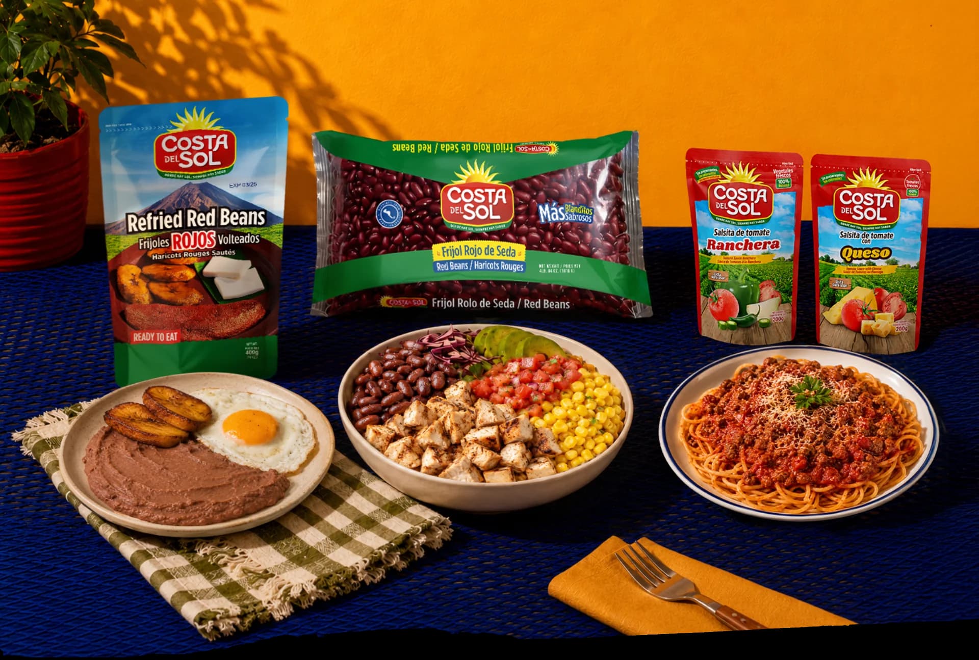 Familia riendo alrededor de la mesa con burritos, un bowl de frijoles rojos con queso y cilantro, arroz con frijoles negros y pollo, y vasos de horchata